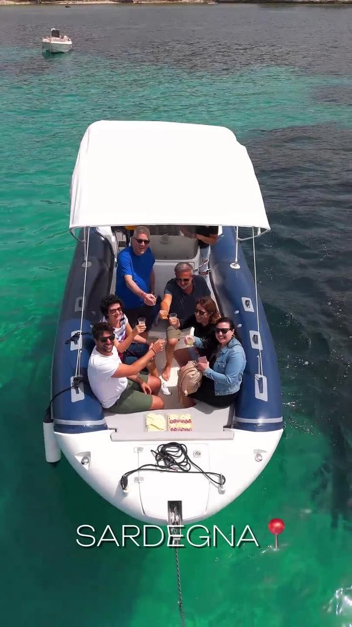 Gommone con passeggeri sull'acqua turchese sotto la falesia